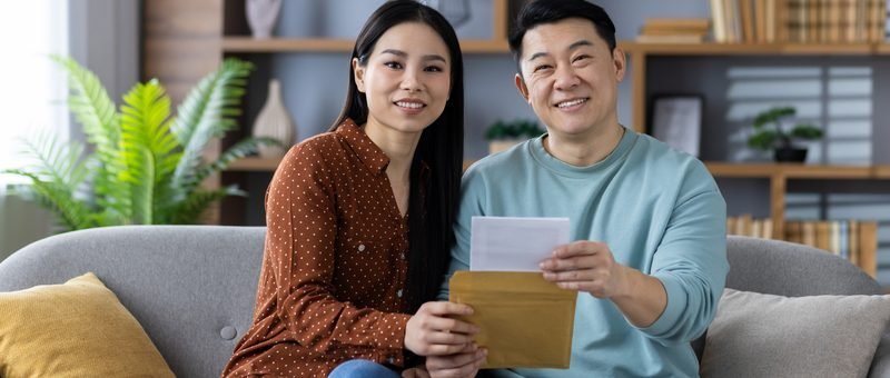 A homeowner at a kitchen table comparing a mortgage statement with a rate chart on a laptop